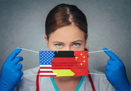 Das Bild zeigt eine Person, die blaue Einweghandschuhe trägt und eine Gesichtsmaske mit den Flaggen der USA, Deutschlands und Chinas hält.