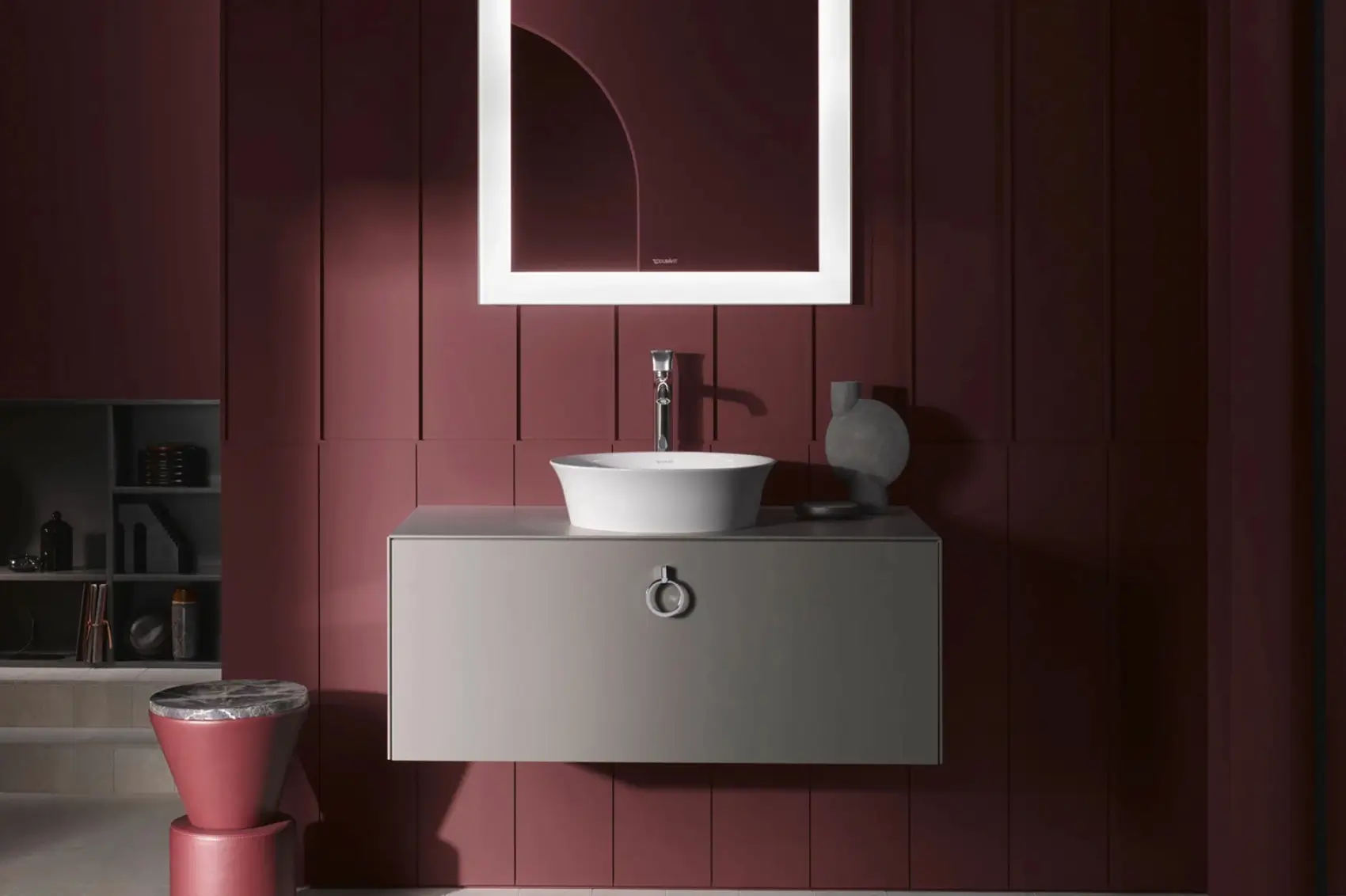 Badezimmer mit roter Wandverkleidung, einem runden Duravit-Waschbecken und einem beleuchteten Spiegel.