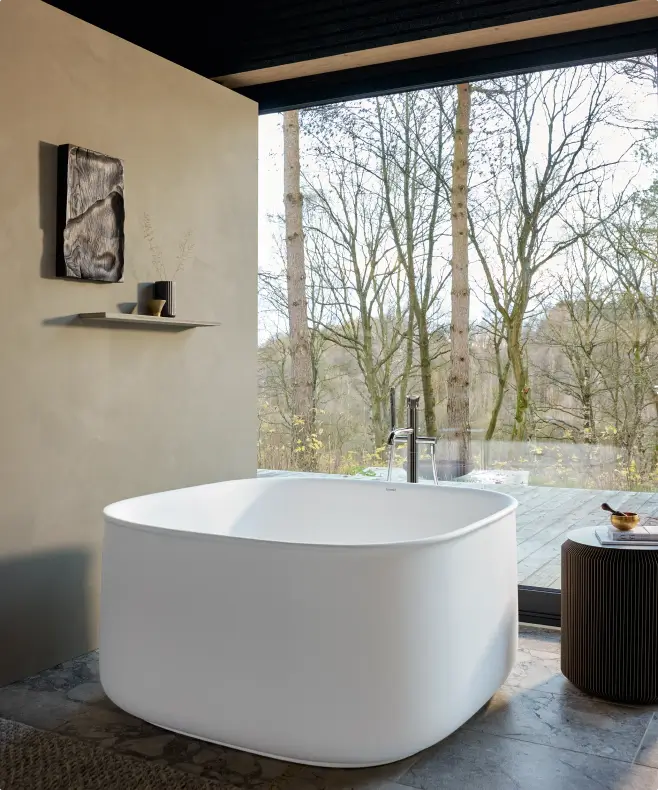 Freistehende Badewanne von Duravit in einem Badezimmer mit Blick auf die Natur durch eine große Glasfront.