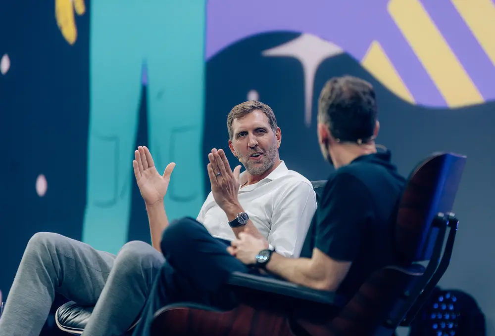 Dirk Nowitzki sitzt entspannt in einem Sessel während eines Fireside Chats auf der OMR-Bühne und gestikuliert lebhaft im Gespräch mit dem Moderator.
