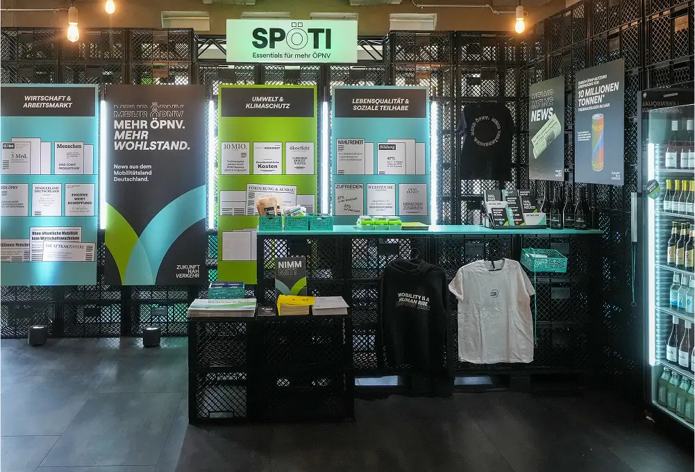 Ein Messestand mit beleuchteten Postern zu Themen wie ÖPNV, Umwelt und Klimaschutz sowie ausgestellten Produkten.
