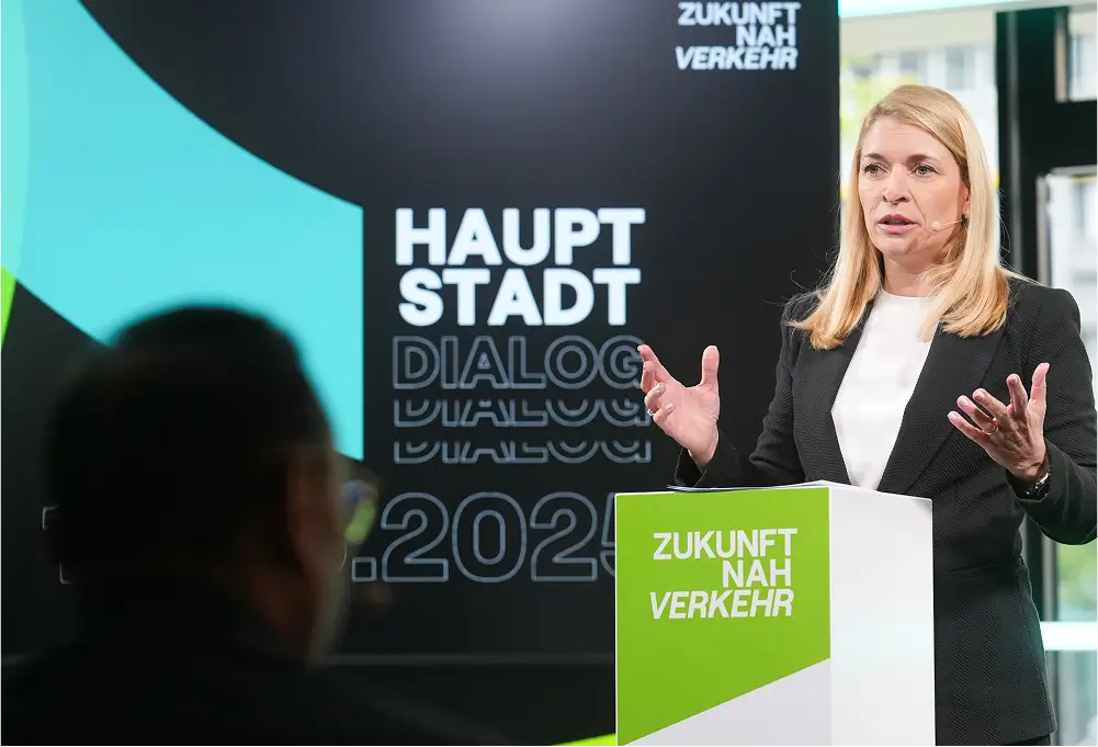 Eine Rednerin hält eine Präsentation vor einem Publikum, begleitet von einer großen Leinwand mit der Aufschrift „Hauptstadt Dialog“.