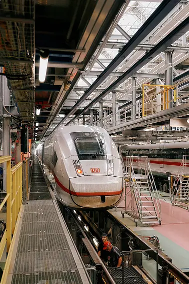Ein ICE-Zug steht in einer modernen Werkshalle auf einer Wartungsplattform.
