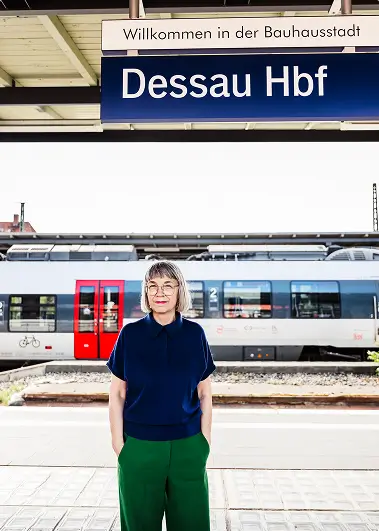 Ein blaues Bahnhofsschild mit der Aufschrift „Dessau Hbf“ unter dem Bahnsteigdach.