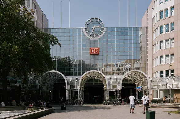Außenansicht eines großen Bahnhofsgebäudes mit DB-Logo und Uhr.