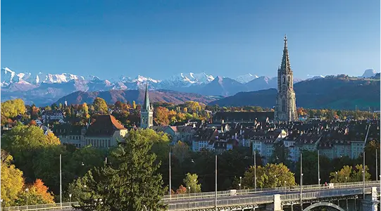 Blick über die Stadt Bern mit dem Berner Münster und den Alpen im Hintergrund.
