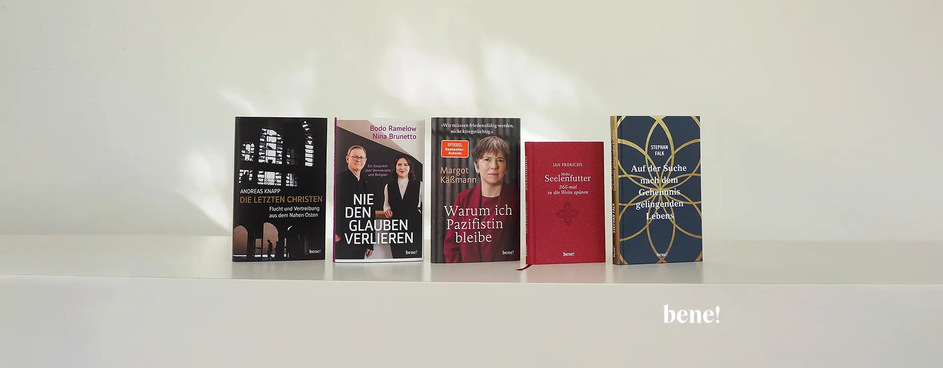 Fünf Bücher zu christlichen und gesellschaftlichen Themen stehen nebeneinander auf einem weißen Regal, darunter „Die letzten Christen“, „Nie den Glauben verlieren“, „Warum ich Pazifistin bleibe“ und „Seelenfutter“. Unten rechts ist das Logo „bene!“ zu sehen.
